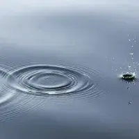 Ein Tropfen Wasser zieht Kreise auf einer Wasseroberfläche